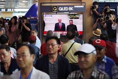 People watch a TV screen showing President Donald Trump and North Korean leader Kim Jong Un, right, at the border villages of Panmunjom in a news report, at the Seoul Railway Station in Seoul, South Korea, Sunday, June 30, 2019.