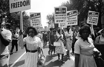 Image: Demonstrators carry signs calling for equal rights and integrated sc