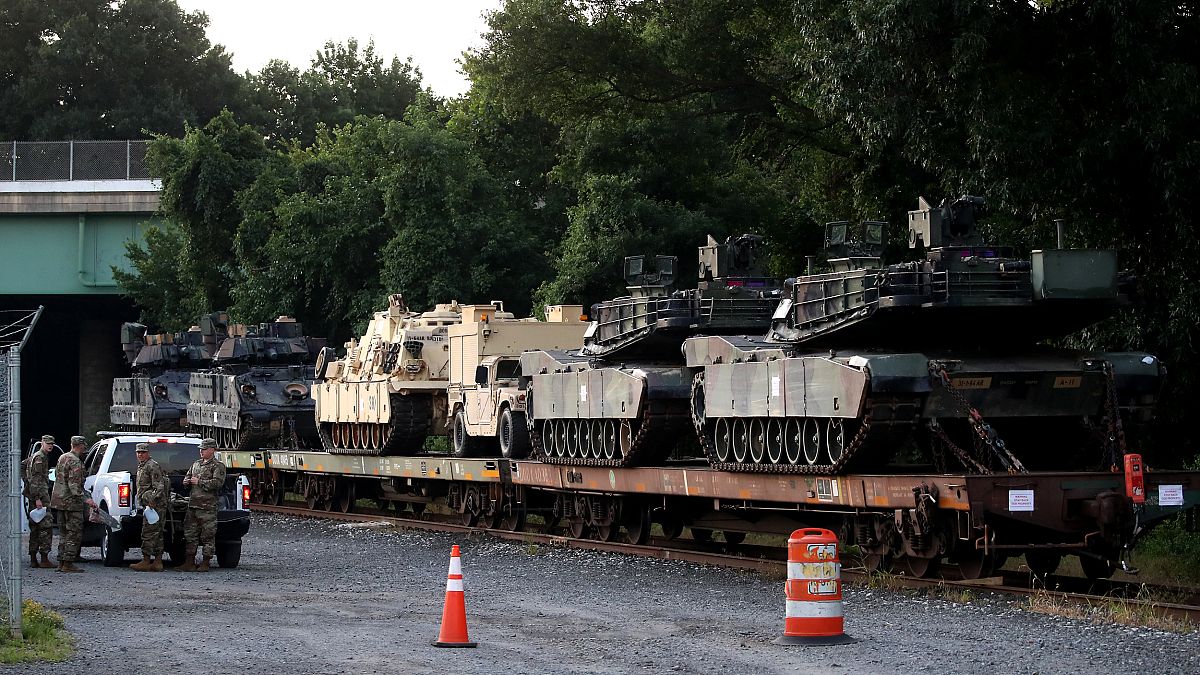 Image: M1A1 Abrams tanks and other military vehicles sit on rail cars in Wa