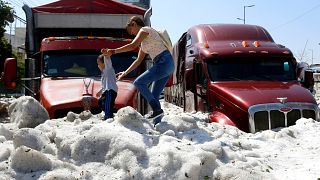 Image: A woman and child walk on a pile of hail in Guadalajara, Mexico, on 
