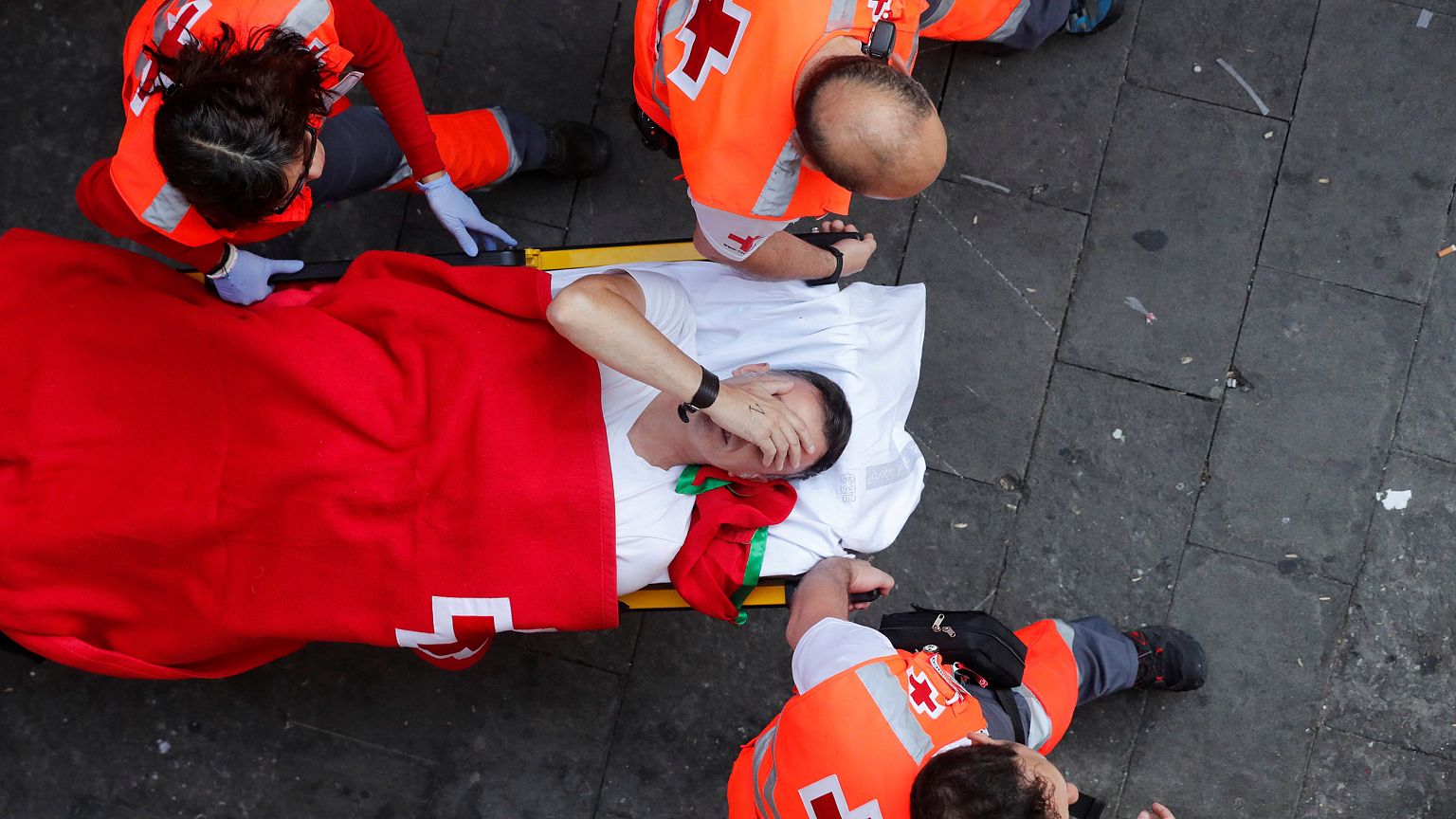 Image: A reveller is helped by medical staff during the running of the bull