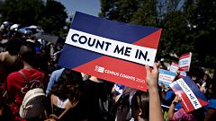 Image: A demonstrator holds a sign denouncing a Trump administration plan t