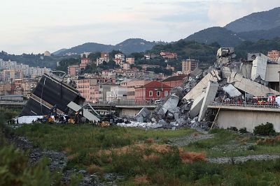Rescuers inspect the rubble and wreckages by the Morandi motorway bridge after a section collapsed earlier in Genoa on Aug. 14, 2018.