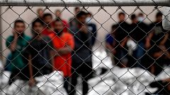 Image: Adult male detainees stand inside a holding area at the Border Patro