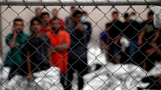 Image: Adult male detainees stand inside a holding area at the Border Patro