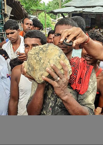 A villager holds a 22 pound meteorite that crashed in a field at Mahadeva village in Madhubani district of the Indian eastern state of Bihar on July 22, 2019.