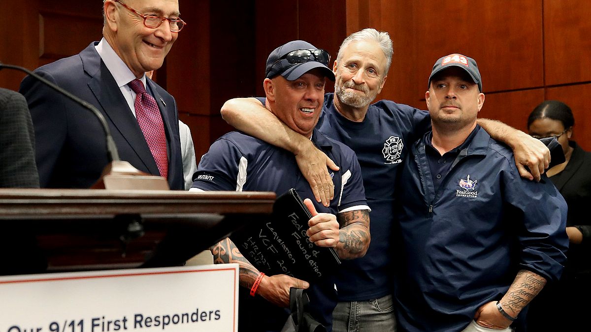 Image: Jon Stewart hugs 9/11 first responders with Sen. Chuck Schumer, D-NY