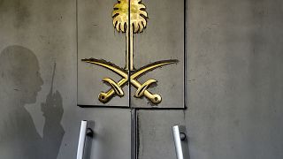 The shadow of a security member of the consulate is seen on the door of the