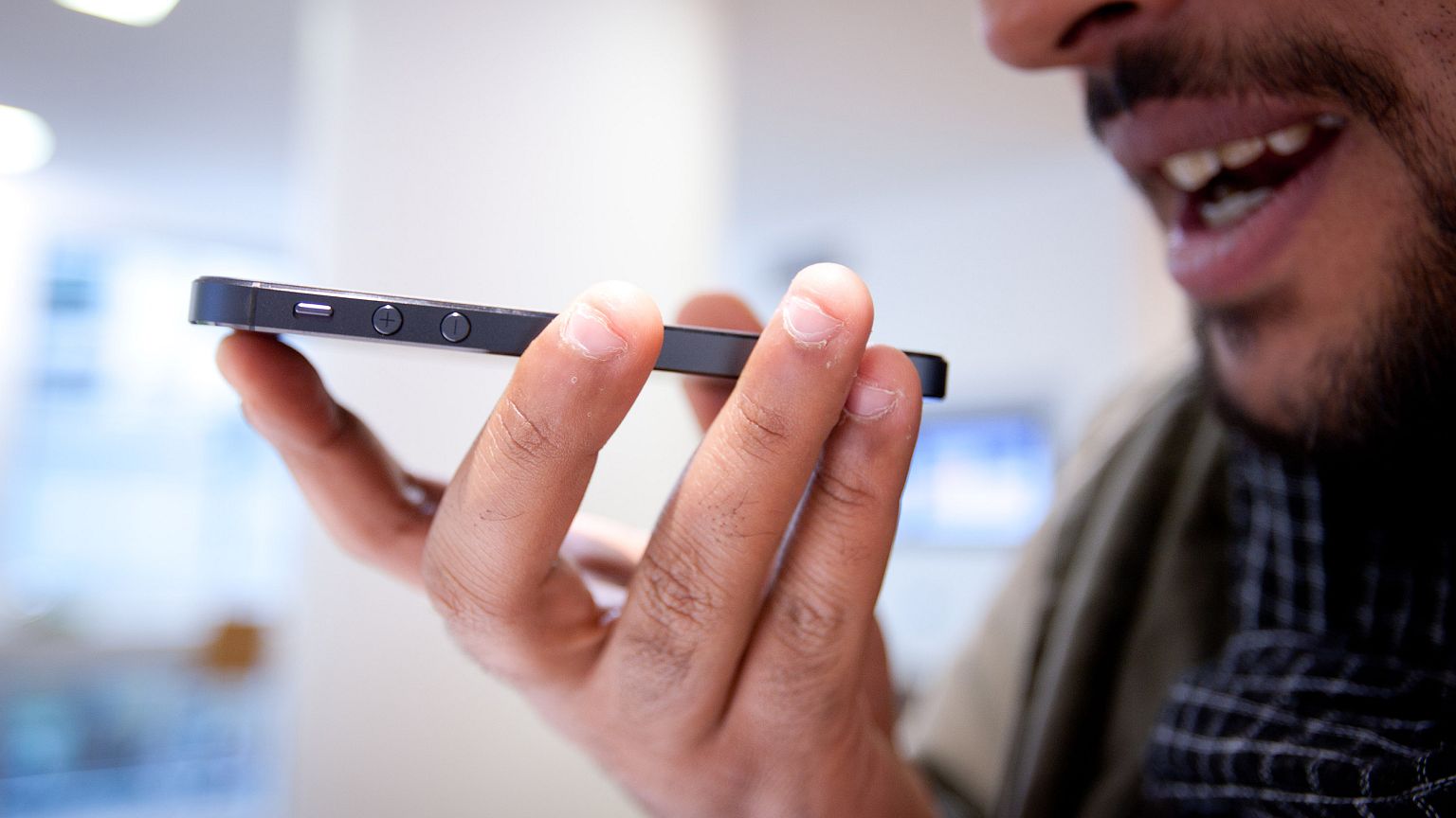 Image: A customer tries the Siri voice assistant function on an iPhone 5.