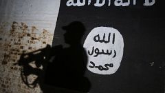 Image: An Iraqi forces member walks past a mural with the ISIS logo in the 