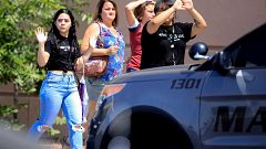 Image: Shoppers exit with their hands up after a mass shooting at a Walmart