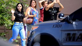 Image: Shoppers exit with their hands up after a mass shooting at a Walmart