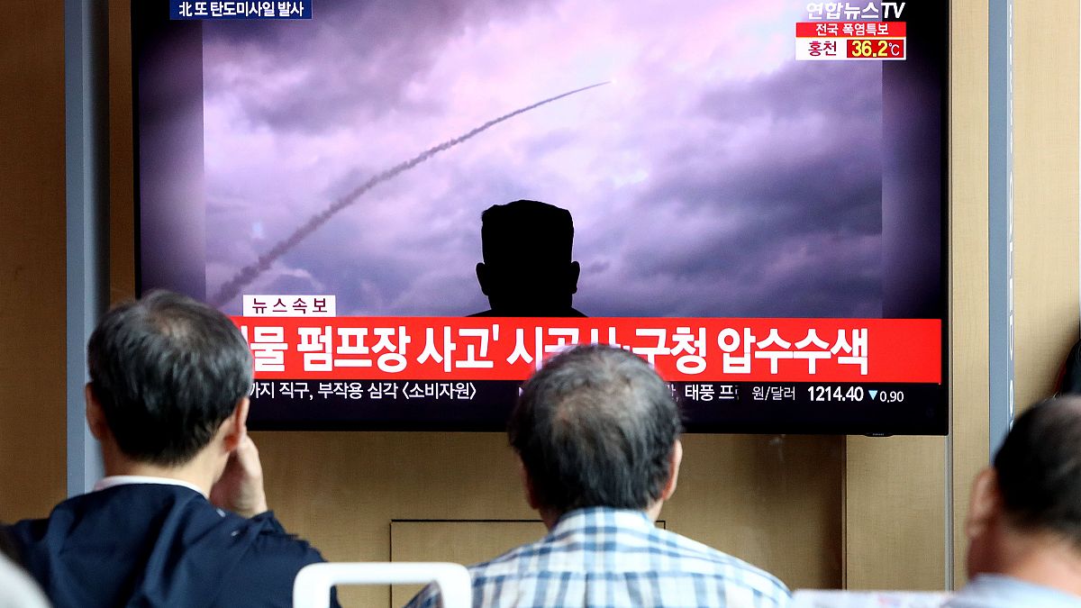Image: People watch a TV showing a file image of a North Korea's missile la