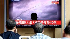 Image: People watch a TV showing a file image of a North Korea's missile la