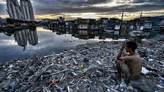 Image: A man sits on the ruins of what was the neighborhood of Pasar Ikan i