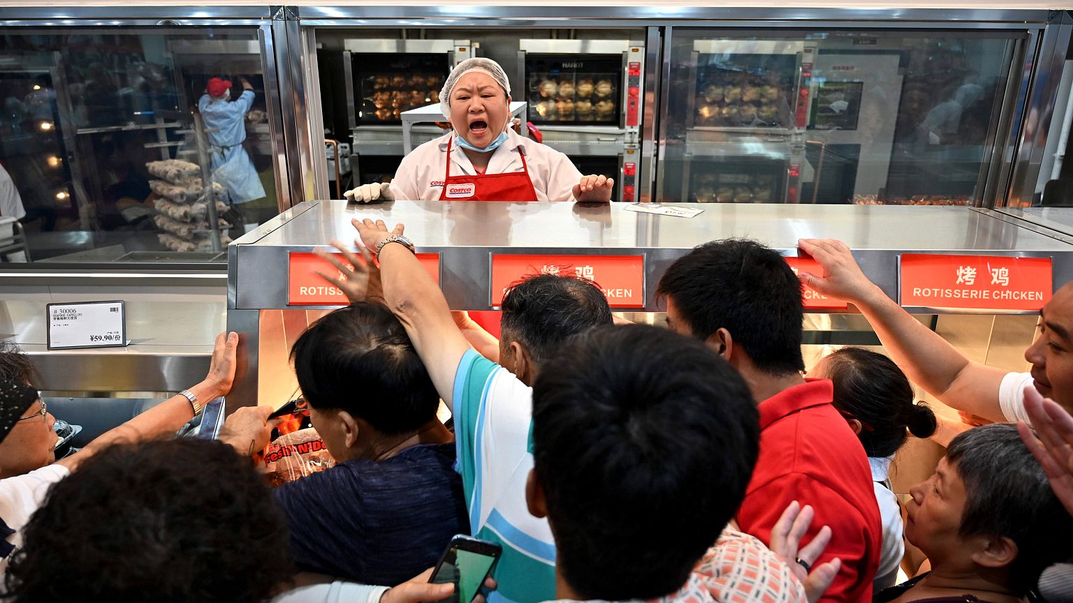 Image: People try to get a roast chicken at the first Costco outlet in Chin
