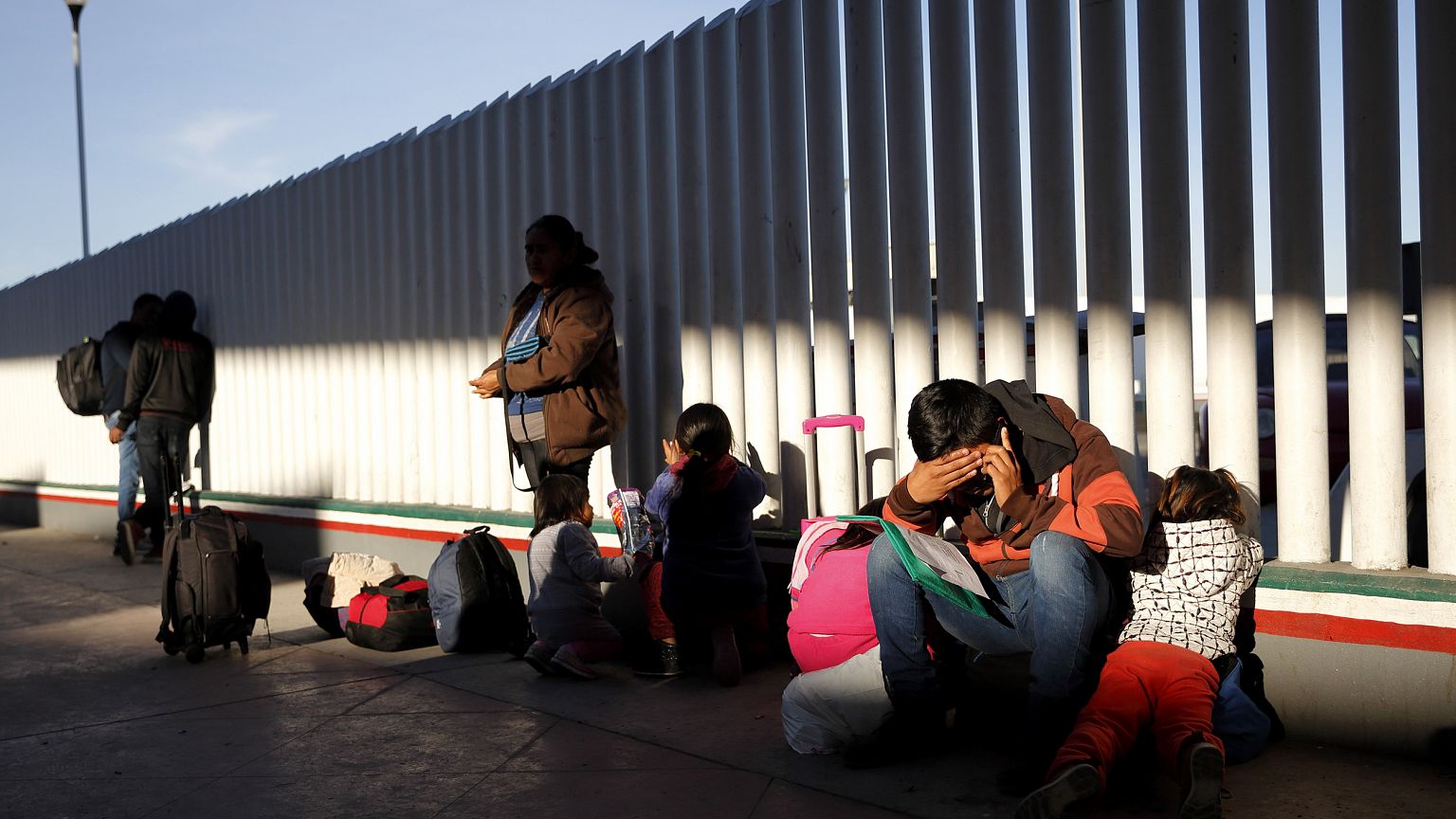 Image: A migrant sits with his children to apply for asylum to the United S