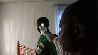 Image: A health official checks the temperature of a school going pupil fro