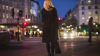 Rear view of woman walking on city street at night