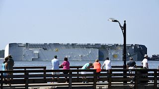 People look at a capsized cargo ship off the St. Simons Island Pier on Sept
