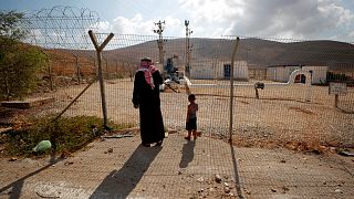 Image: Palestinians stand at a fence separating the Jordan Valley and the I