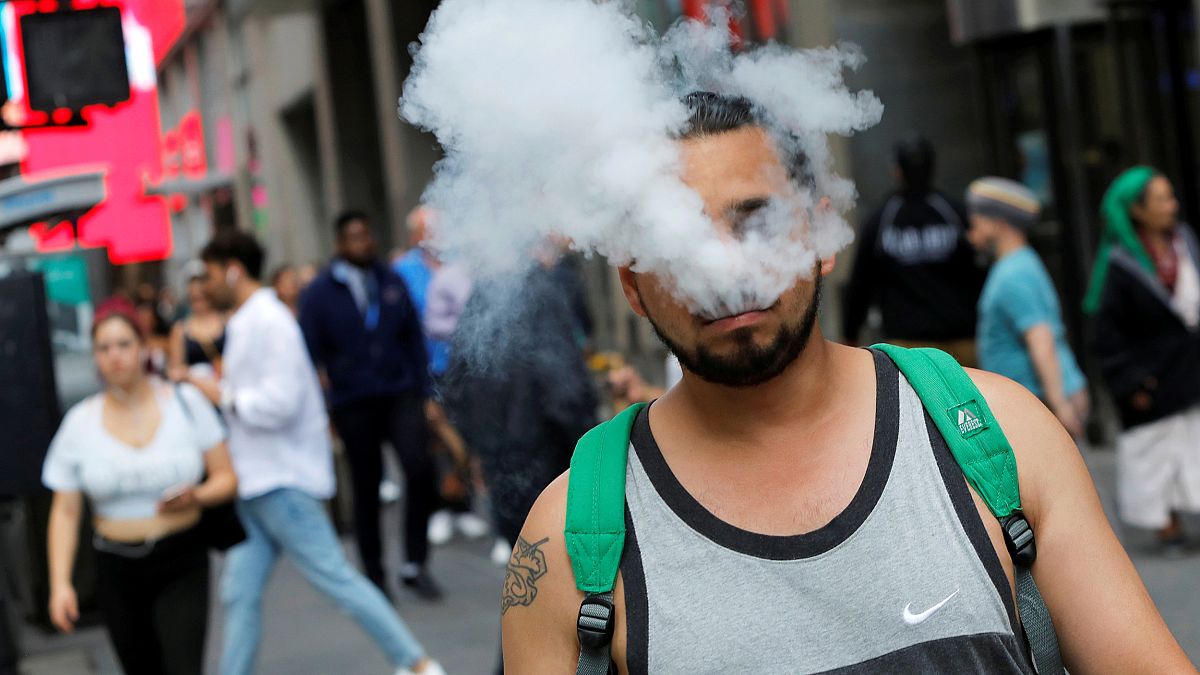 Image: A man uses a vape as he walks on Broadway in New York City