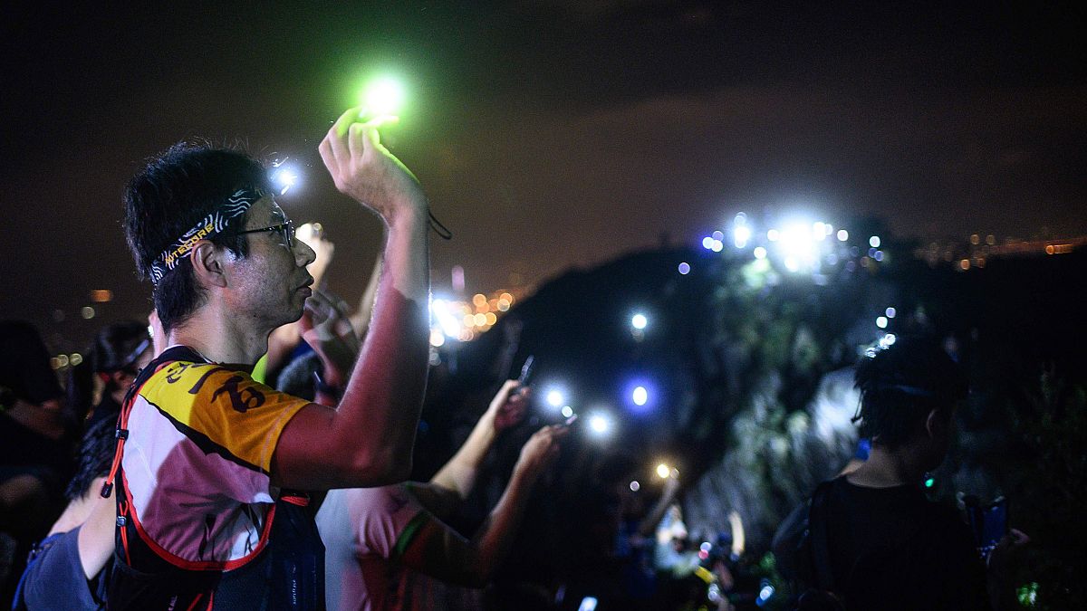 Image: A protester lights up a laser beam at the hill top of Lion Rock in H