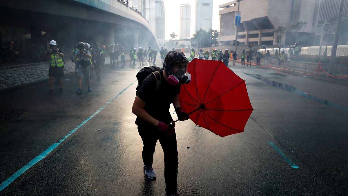 Image: An anti-government protester protects himself with an umbrella in Ho