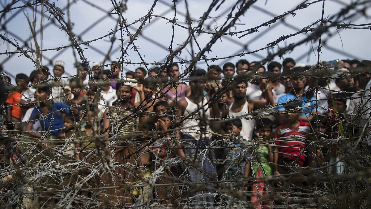 Image: Rohingya refugees gathering behind a barbed-wire fence in a temporar