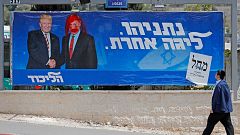 Image: An Israeli man looks at a defaced election billboard for the Likud p