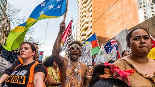 Image: A man wearing the traditional dress of the Solomon Islands march on 