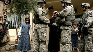 Image: An Iraqi man answers questions from U.S. soldiers with the help of a