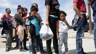 Image: Central American migrants stand in line before entering a temporary 