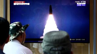 Image: People watch a TV showing a file image of a North Korea's missile la