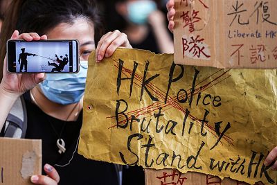 People hold up signs and a mobile phone as they gather at West Kowloon Law Courts Building to show their support to 96 anti-government protesters who were arrested days ago in Hong Kong.
