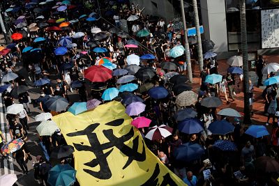 Shielded under umbrellas, hundreds of demonstrators clogged a thoroughfare in Hong Kong\'s central business district.