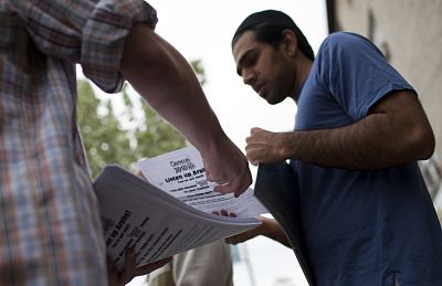 Arab-American men exiting a mosque following Friday prayers take fliers encouraging the arab population to fill out their 2010 census forms in Brooklyn, New York on April 9, 2010.