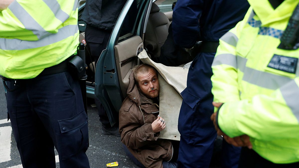 Image: Police officers remove a protester attached to a car during Extincti