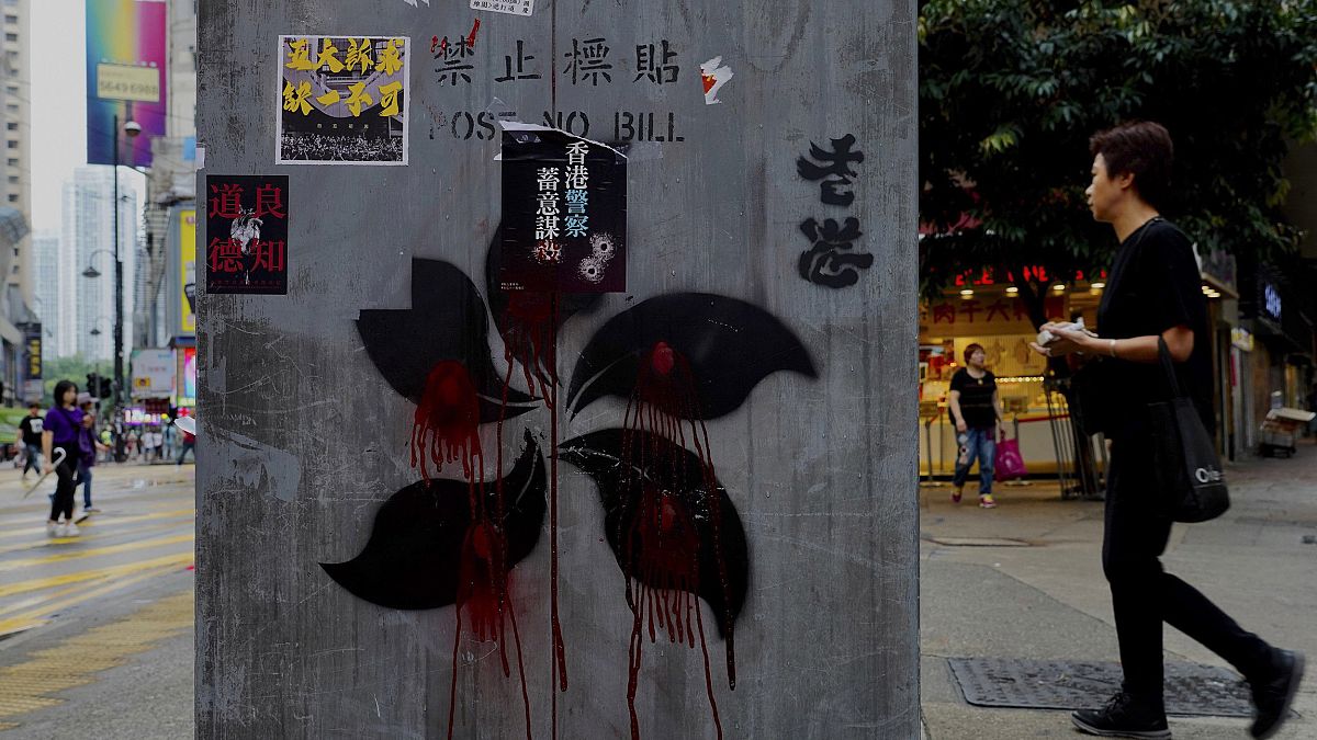 Image: People walk near graffiti on a pillar which shows Hong Kong Special 