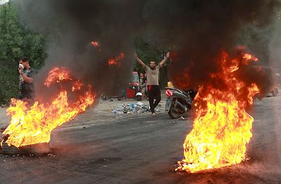 Anti-government protesters set fires and close a street during a demonstration in Baghdad, Iraq, Sunday, Oct. 6, 2019.