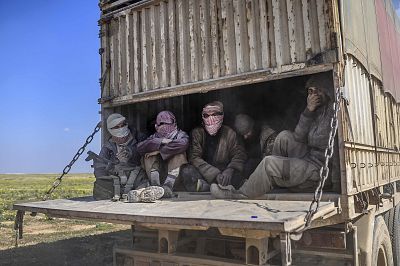 A truck carrying men, identified as Islamic State group fighters who surrendered to the Syrian Democratic Forces, leaves ISIS\' last holdout of Baghouz on Feb. 20.