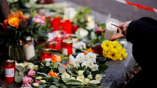 Image: A woman lights a candle at a makeshift memorial in Halle, Germany Oc