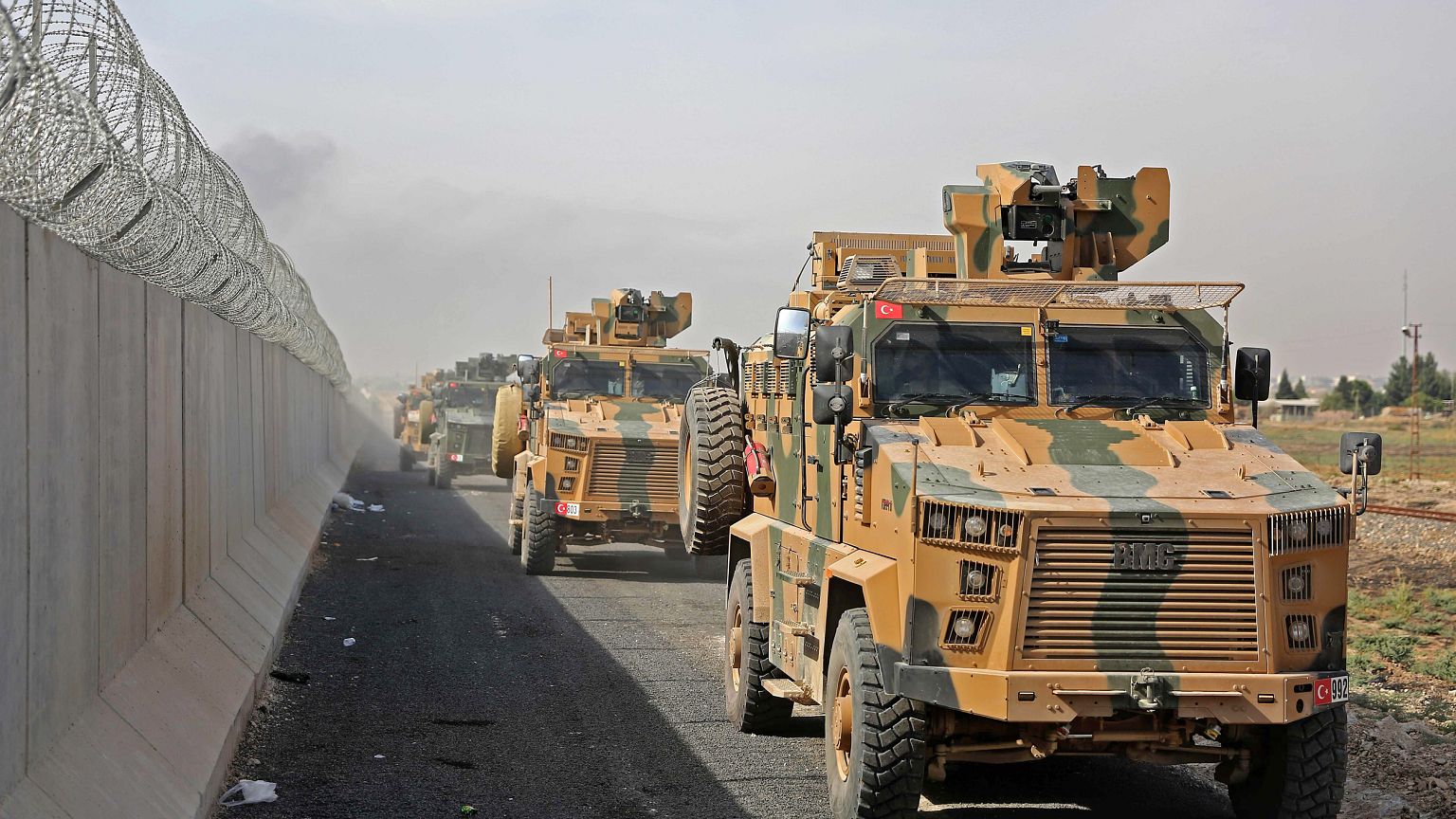 Turkish armored vehicles drive along the Turkish side of the border as they