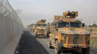 Turkish armored vehicles drive along the Turkish side of the border as they