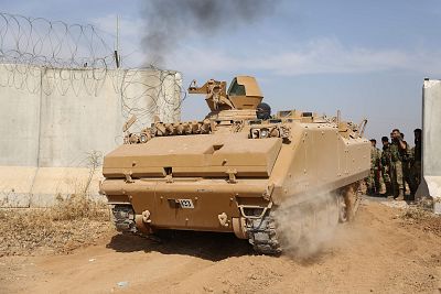 Pro-Turkish Syrian fighters drive an armored personnel carrier across the border into Syria as they take part in an offensive against Kurdish-controlled areas in northeastern Syria launched by the Turkish military, on Friday. 