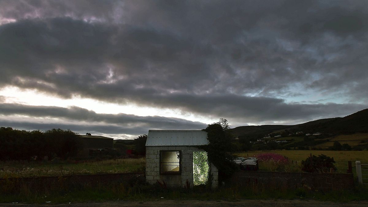 Image: A former customs guard hut is illuminated on the Irish border on Aug
