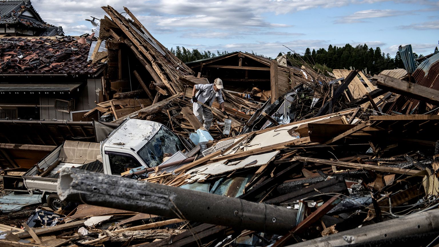 Image: A man looks through debris of a building that was destroyed by a tor
