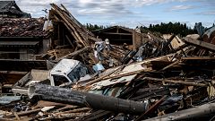 Image: A man looks through debris of a building that was destroyed by a tor