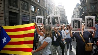 People holding an Estelada and pictures of Catalan politicians as they walk