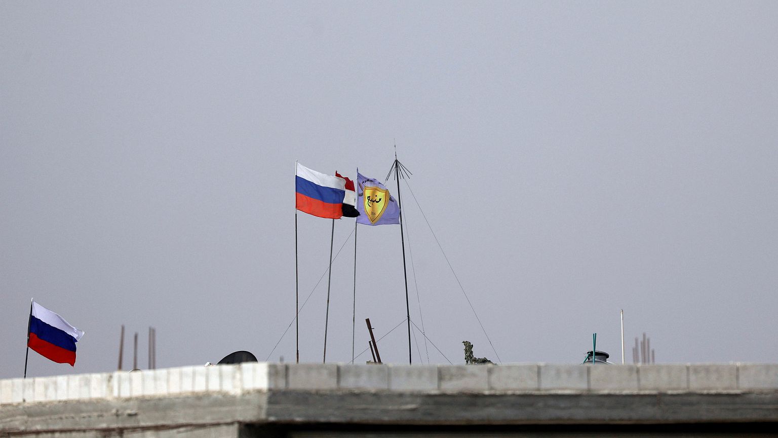 Image: Russian, Syrian and Manbij military council flags flutter near Manbi